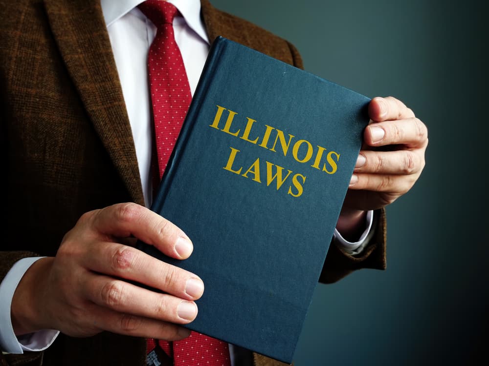 State Illinois law. A man in a suit is holding a book.