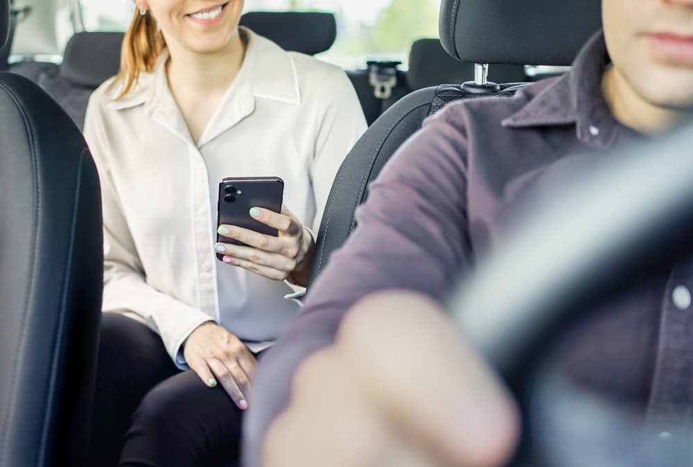 Rideshare car passenger using phone during traveling.