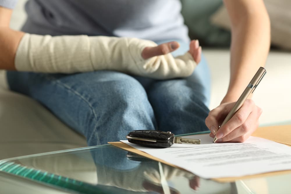 A lady hands with broken arm signing insurance document after rideshare accident at home