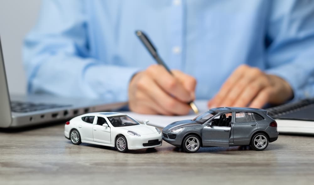 A car accident attorney working and two toy cars are colliding each other on the table