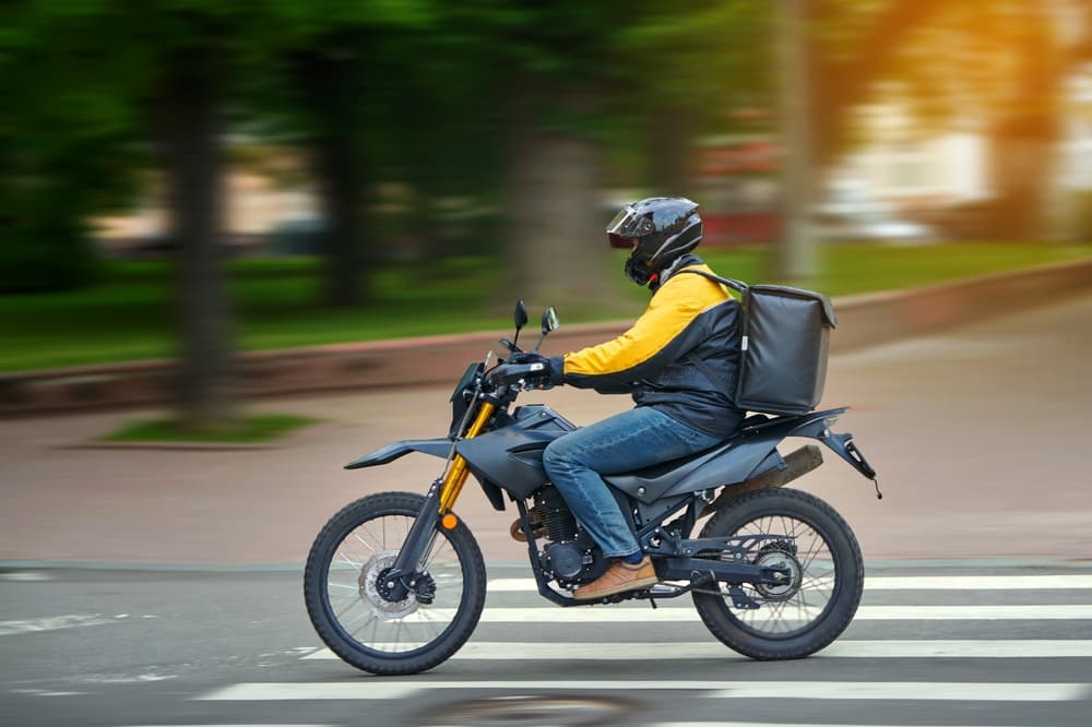 Food delivery motor bike driver with backpack behind back is on his way to deliver food.