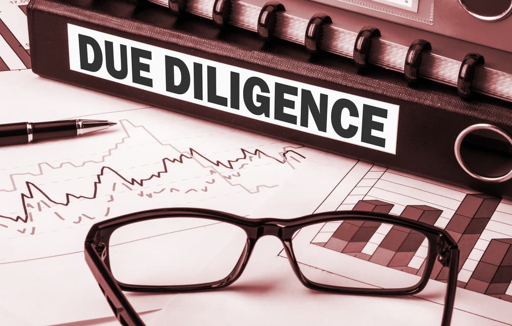 Close-up of a business document file labeled "Due Diligence," representing the process of reviewing and analyzing company information before a transaction or decision.